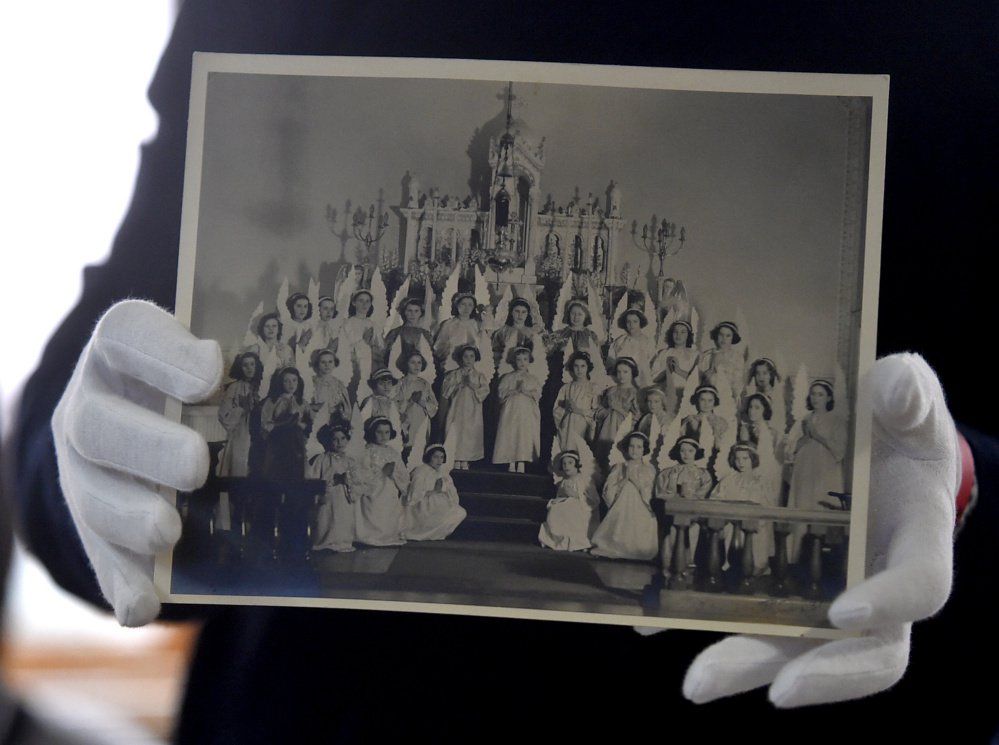 Colby College student Muheb Esmat holding a photograph of children dressed as angels at the Notre Dame School, Waterville, Maine, gelatin silver print, ca. 1910s, Therese Bernier Small Family Photograph Collection, Special Collections, Colby College Libraries. Photograph by Michael G. Seamans / centralmaine.com (30098)