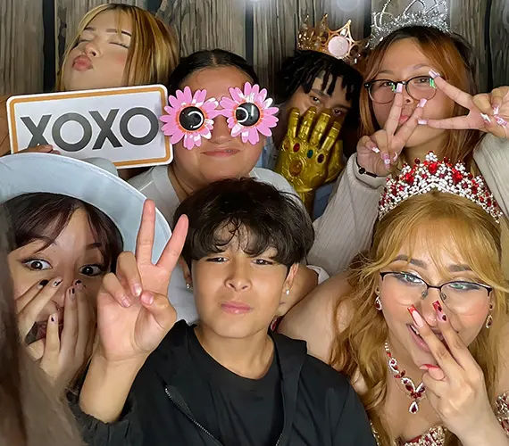 quinceanera-group-photo-booth-girls-tiara-peace-sign-glamoor Group of seven teen girls posing at Glamoor Photo Booth, with the quinceañera wearing a tiara and two girls making peace signs