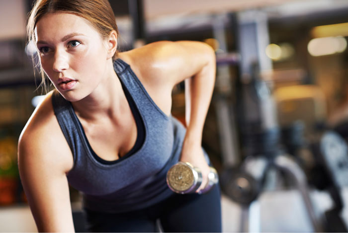 In fitness studio, people of different ages engaged in Pilates. Young girl  coach performs exercise with