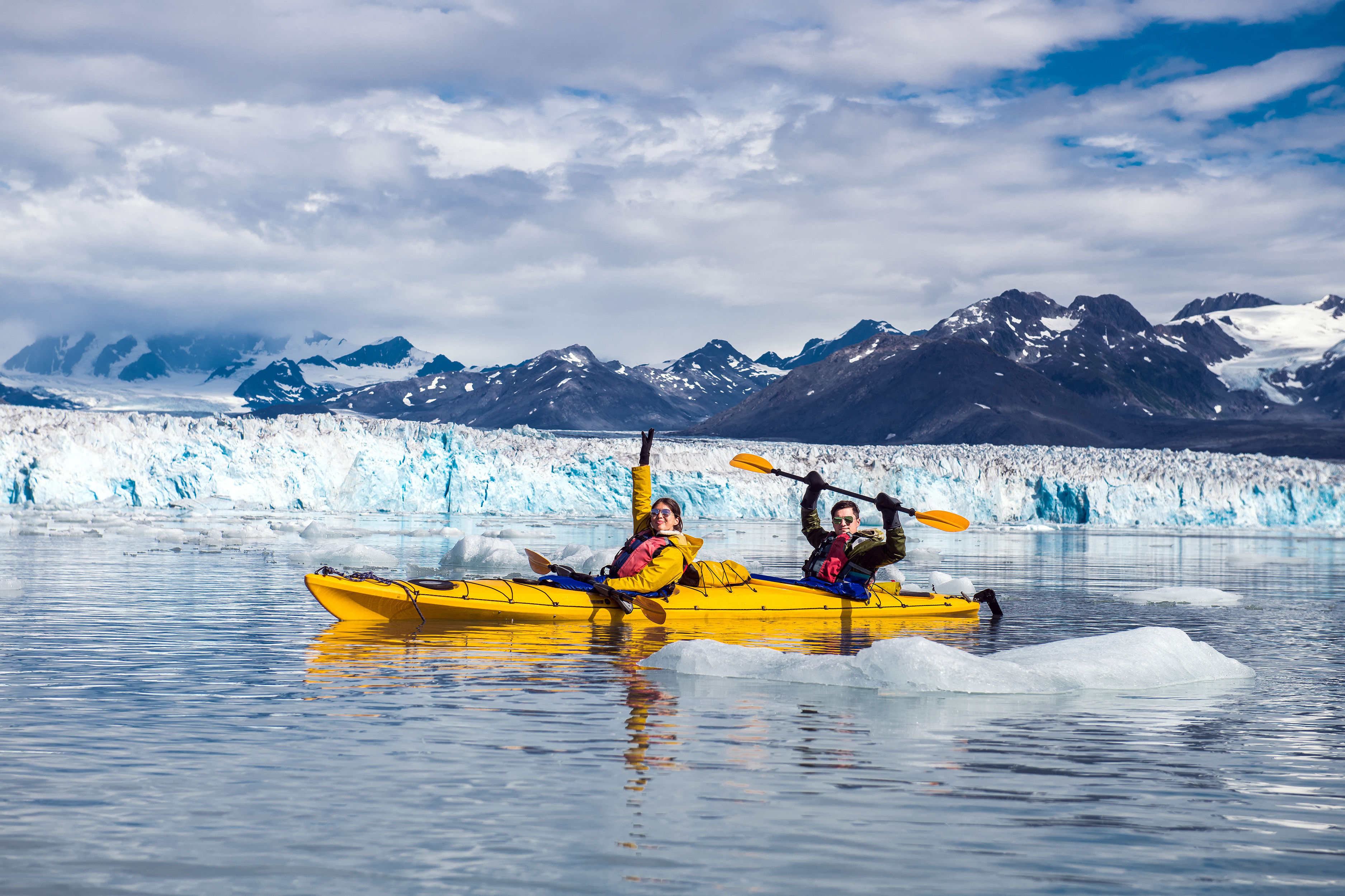 Happy couple enjoys ocean kayaking bear glacier during their vacation trip to in Alaska