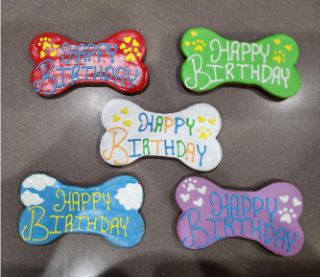 Sam's birthday cookies in the shape of a bone that say 'happy birthday'