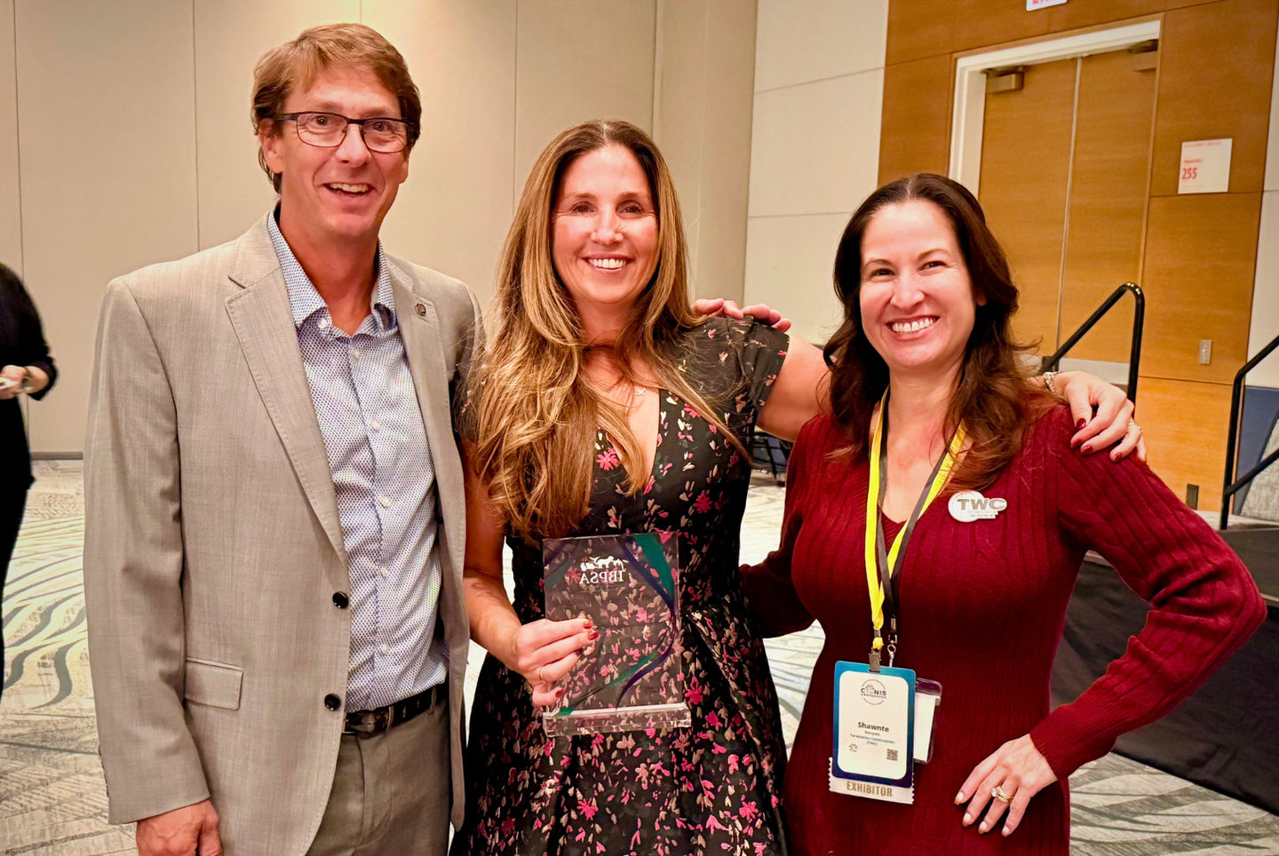 Jeni Mather (center) stands holding the IBPSA &ldquo;IBBY&rdquo; Award for Industry Leadership, alongside fellow industry professionals [Name] (left) and Shawnte Marquez (right)