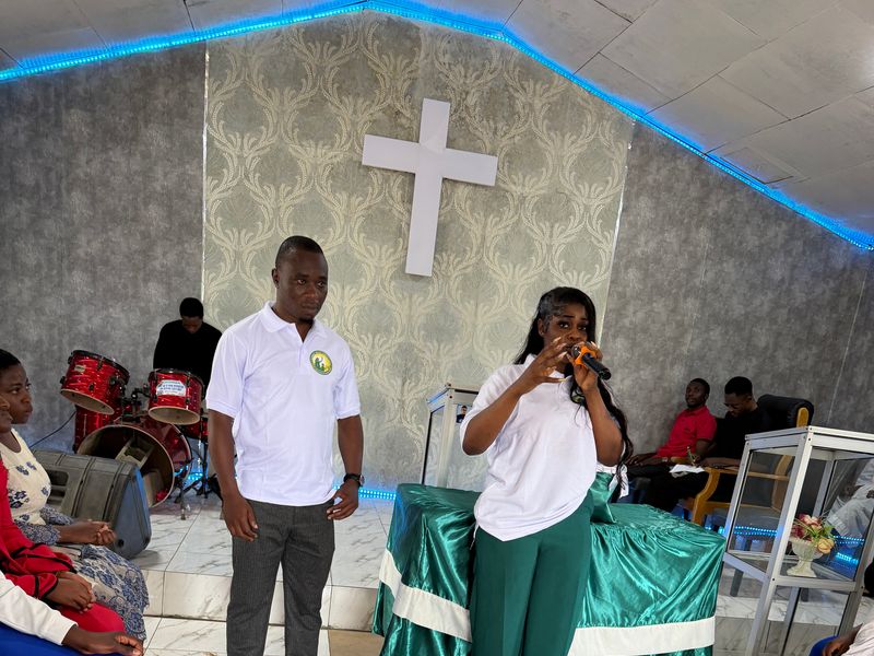 A Foundation team member speaks into a microphone to an audience in the Youth Centre hall