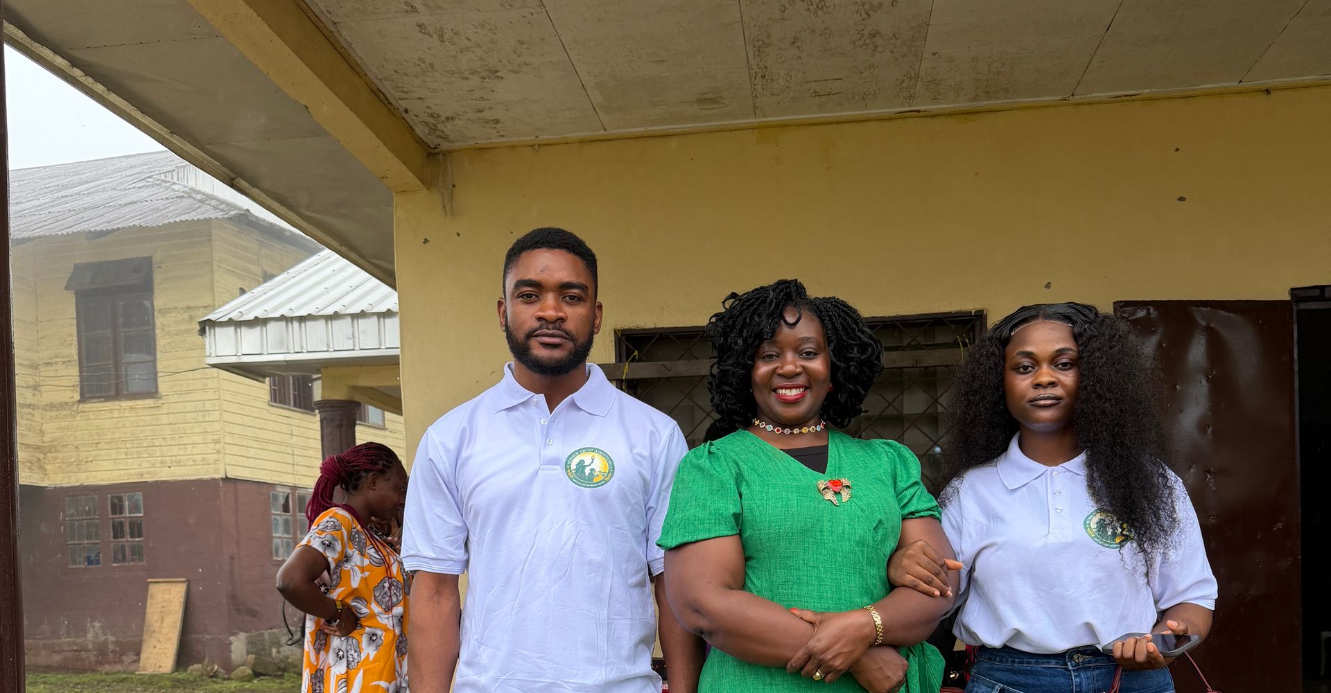 Three members of the Foundation team, two in its logo polo shirts, outside a school building