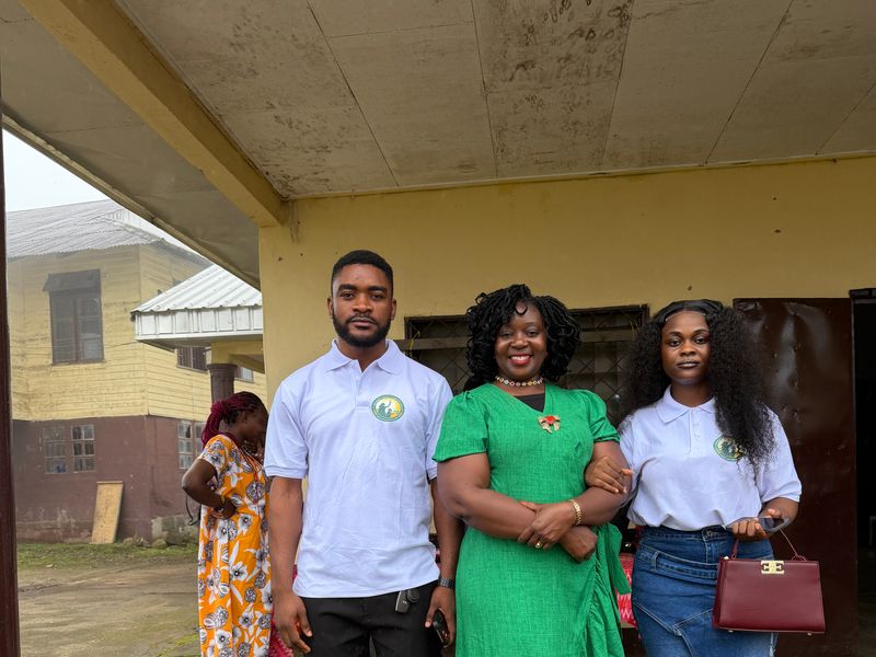 Three members of the Foundation team, two in its logo polo shirts, outside a school building
