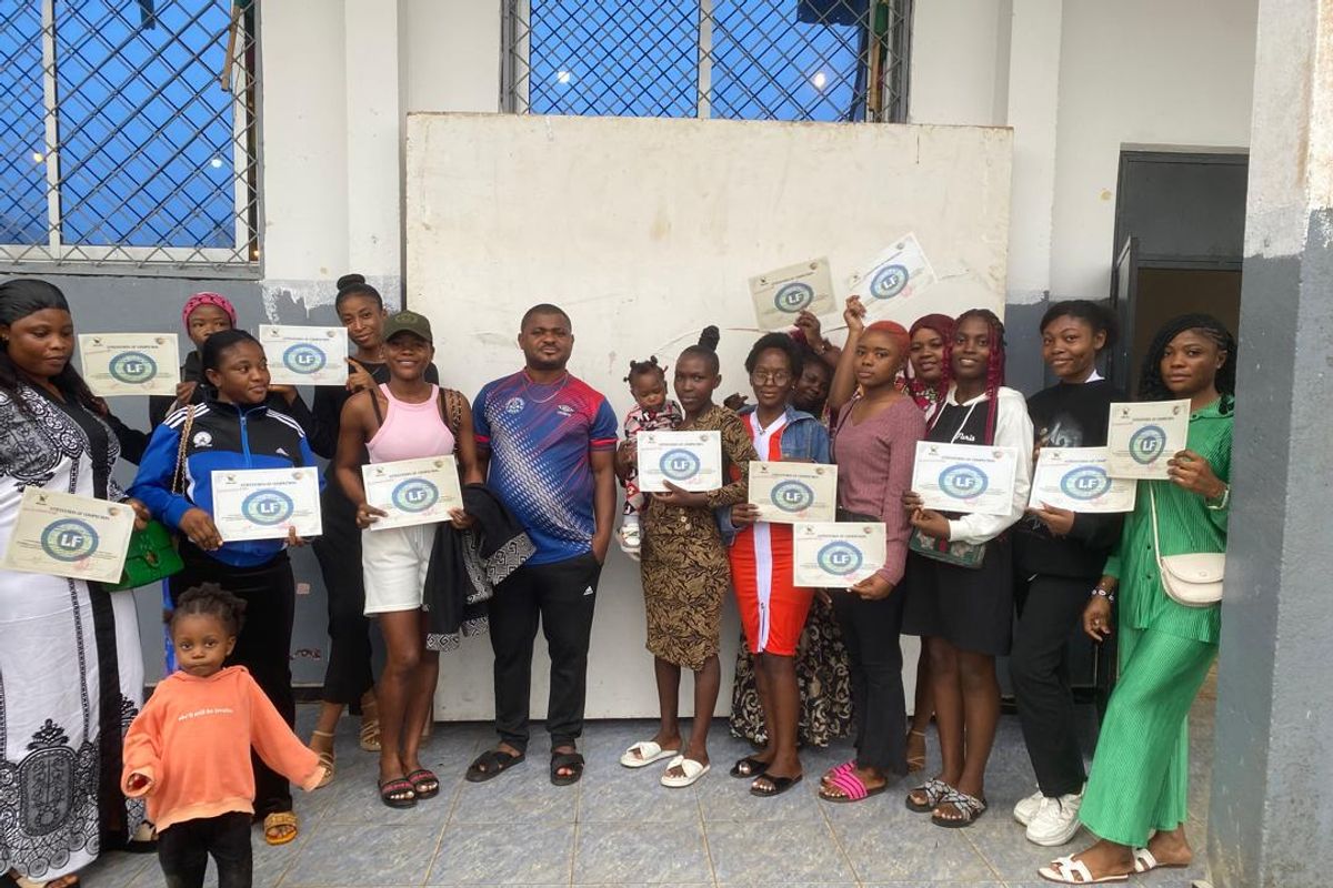 A group of young people hold up certificates outside a building