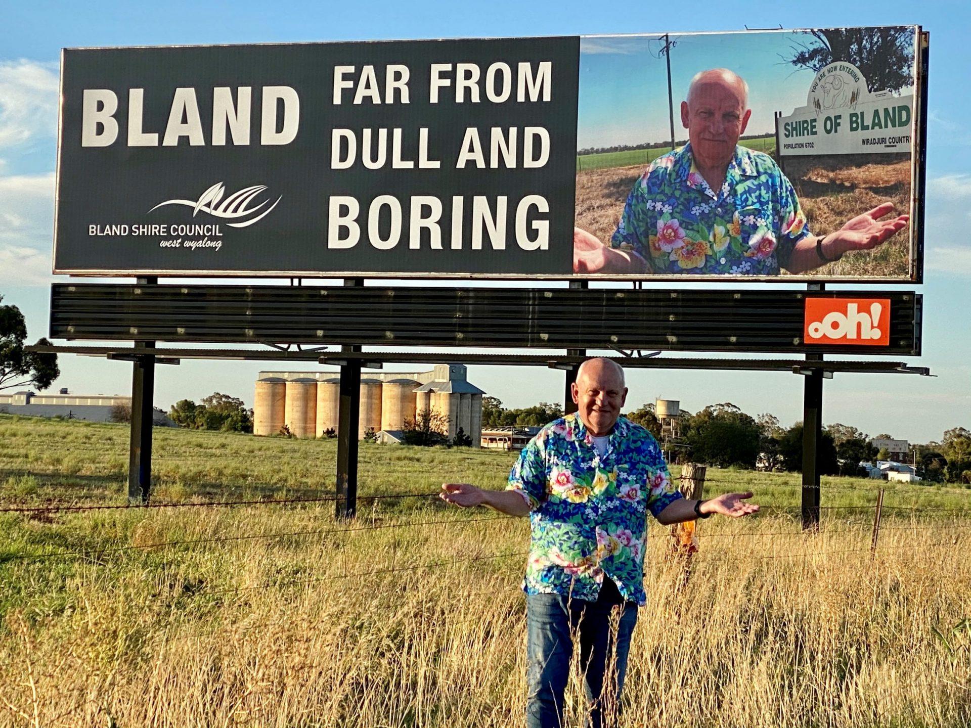 Bland Shire Council's General Manager, Ray Smith, at the the Bland, Dull and Boring billboard on the Newell Highway, Bland Shire, Australia. Image taken by Donna Smith