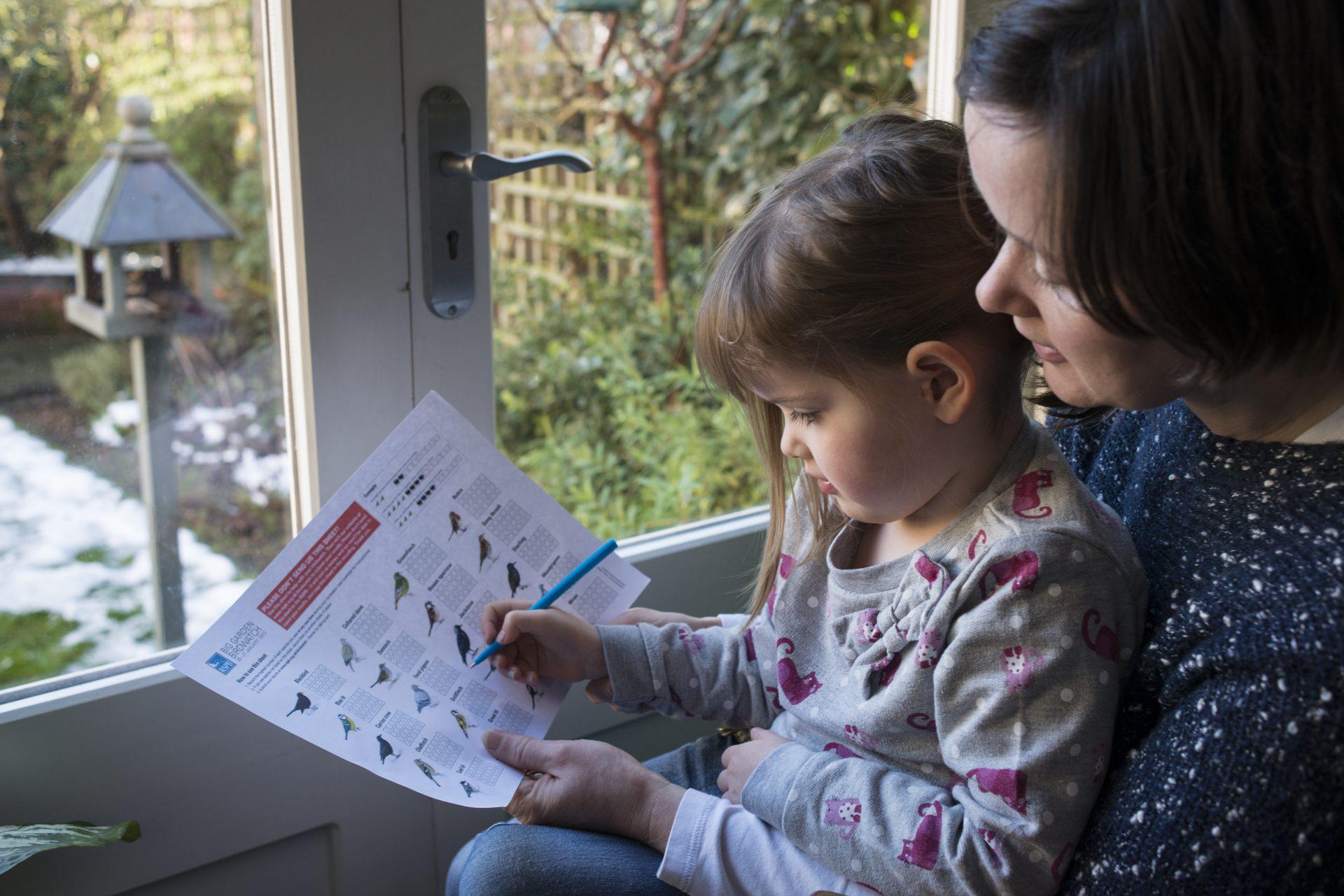 Mother and her daughter counting birds in their garden, Bedford, UK