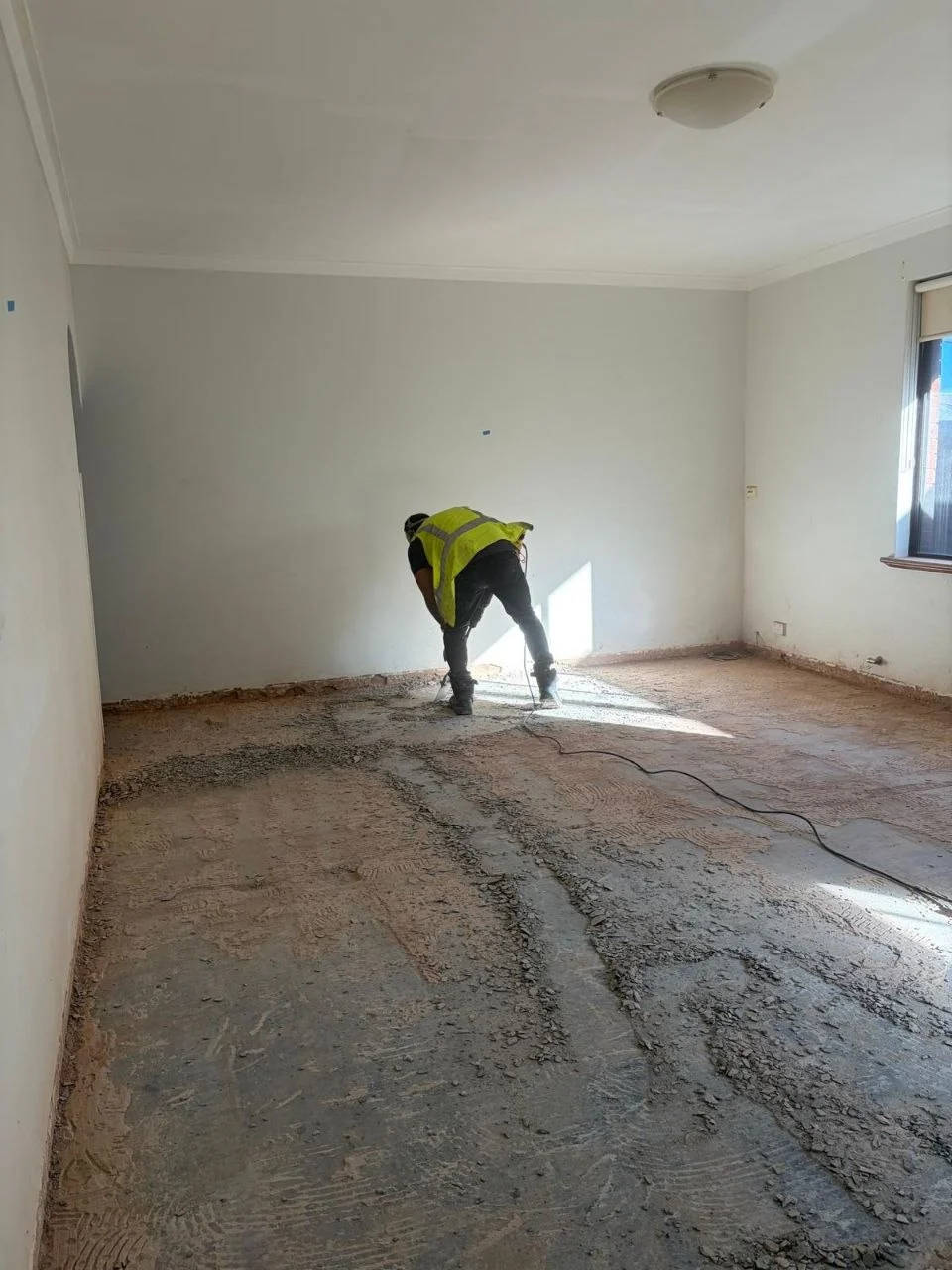 Worker preparing a bare concrete floor on a Perth job