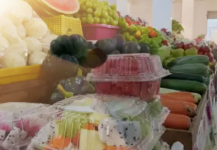 Una fotografía vibrante y colorida del pasillo principal del Mercado de Santiago, mostrando puestos de frutas y verduras frescas con gente comprando, capturando la energía del lugar.