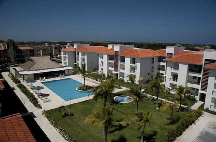 View of the main pool, tropical gardens, and apartment buildings at Karibo Punta Cana hotel.