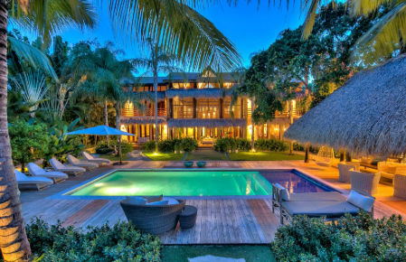 Luxury beachfront restaurant at Tortuga Bay Punta Cana, with a wooden terrace over turquoise water and traditional cane-roof architecture.