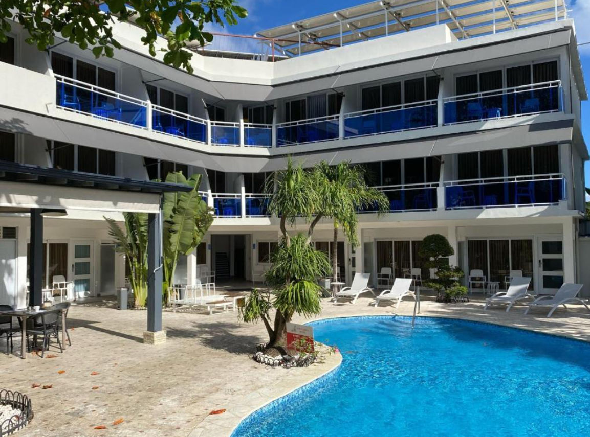 Curved swimming pool with lounge chairs in the courtyard of New Garden Hotel in Sosua, Dominican Republic