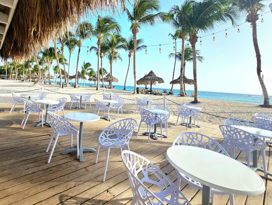 Piscina al aire libre con camastros y mesas junto a la playa en un resort tropical de Punta Cana bajo un cielo soleado