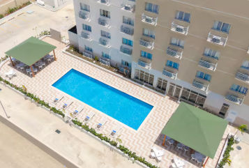 Vista aérea del hotel Wyndham Garden El Morro Montecristi con su piscina, áreas exteriores y estacionamiento rodeados de vegetación natural