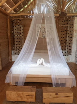 Bungalows ecologicos con techos de paja en Samo Eco Lodge iluminados con luces de cadena al anochecer en Las Terrenas