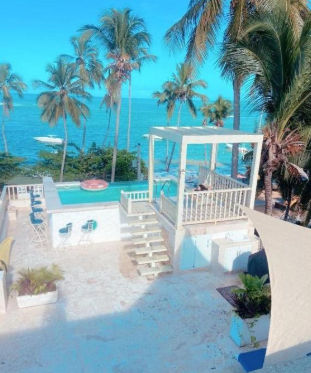 Outdoor swimming pool surrounded by palm trees and blue lounge chairs at Casa Marina Bay Samana resort