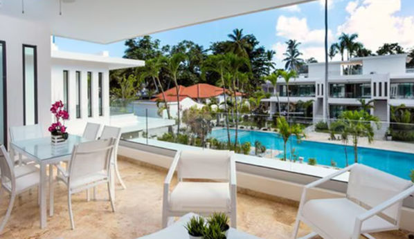 Aerial view of the pool area at Louisa Hotel Las Terrenas, surrounded by palm trees and modern white villas
