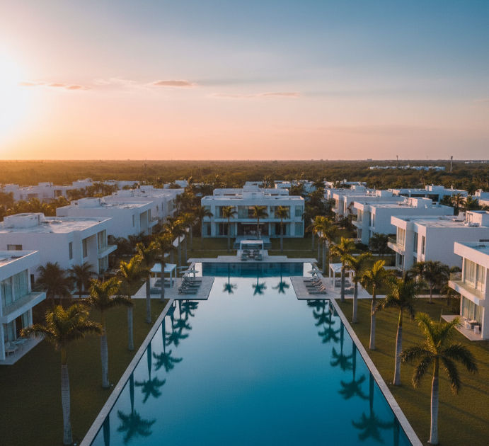 Lujosa residencia moderna en desarrollo en Yucatán con piscina y palmeras.