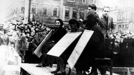 Mujeres judías en Linz, Austria, se exhiben en público con un cartel que indica 