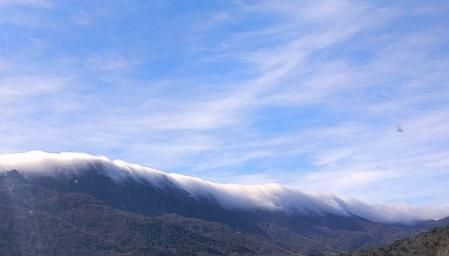 La montaña cubierta en su parte superior por la niebla caída hace que en su conjunto parezca una ola gigante.