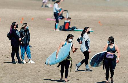 GRAFCVA3745. VALENCIA, 12/04/2021.- Un grupo de jóvenes disfruta de la playa de la Malvarrosa llevando mascarillas cuando este lunes el Diari Oficial de la Generalitat Valenciana publica la nueva resolución de la Conselleria de Sanidad sobre el uso de la mascarilla para contener el coronavirus, que entre otras cuestiones regula cómo debe utilizarse en lugares como la playa y las piscinas. EFE/Kai Försterling