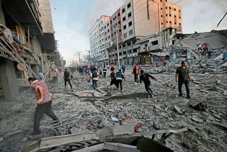 TOPSHOT - Rescuers and people gather amidst the rubble in front of Al-Sharouk tower that collapses after being hit by an Israeli air strike, in Gaza City, on May 12, 2021. - An Israeli air strike destroyed a multi-storey building in Gaza City today, AFP reporters said, as the Jewish state continued its heavy bombardment of the Palestinian enclave. (Photo by Mohammed ABED / AFP)