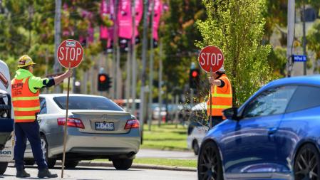 Dos trabajadores de control de tráfico con señales de Stop, en la ciudad australiana de 
Melbourne.