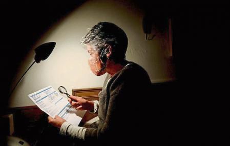 foto XAVIER CERVERA 16/01/2021 una mujer mayor mira con lupa la letra pequena de la factura de la luz, electricidad, ..porque no acaba d entender la subida y tarifas de estos dias de necesidad con temperaturas extremadamente frias... con poca luz, y cierta penumbra en su casa donde vive sola (con mascarilla por la pandemia covid coronavirus ,entre segunda y tercera ola)