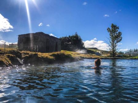 Mujer nadando en la piscina geotermal en fludir secreto Laguna Islandia