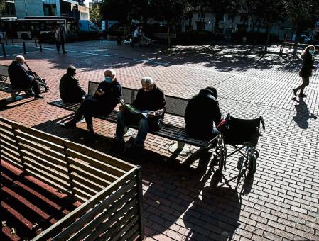 foto XAVIER CERVERA 18/11/2021 tres pensionistas, jubilados ,personas mayores, ancianos, sentados en un banco (y otro en su silla de ruedas) de una plaza del distrito de sant andreu, barcelona, en un soleado jueves de otoño