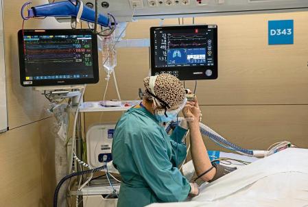 Un paciente de Covid-19 hospitalizado en un box de la UCI del hospital de la Vall d’Hebron coincidiendo con el repunte de ingresos a causa de la cuarta ola de la pandemia. Una sanitaria estabilizando al paciente tras haber sido trasladado