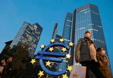 (FILES) In this file photo taken on October 21, 2020 people wearing face masks walk in front of the euro sign at the former ECB headquarters in the city center of Frankfurt am Main, western Germany. - The European Central Bank is expected Thursday to unleash more stimulus to help shore up a eurozone economy devastated by the coronavirus pandemic, analysts said, in a move eagerly awaited by financial markets. The Frankfurt institution already has a 1.35-trillion-euro ($1.6-trillion) emergency bond-buying programme in place, but ECB chief Christine Lagarde all but promised in October that extra support was on the way. (Photo by Yann Schreiber / AFP)