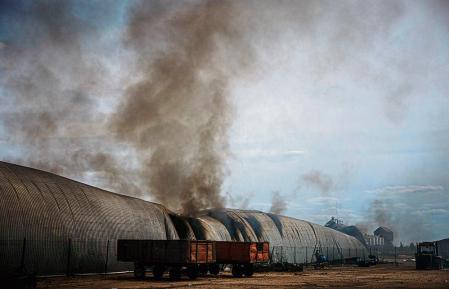 TOPSHOT - Smoke billows from a burning storage building after having been shelled in the village of Temyrivka on May 4, 2022, amid the Russian invasion of Ukraine. - The blaze in a football field-length storage building has been burning at least a day #{emoji}151; but there's no firefighters in Temyrivka because everyone has evacuated, leaving the black smoke to rises unhurriedly. That village is in a no man's land where the two sides are so close, in some places about 3 kms, that Ukrainian troops using binoculars can see the Russians digging at their positions. (Photo by Dimitar DILKOFF / AFP)