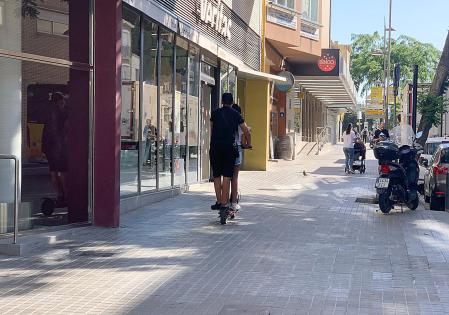 Dos personas en un patinete eléctrico circulando por la acera&nbsp;