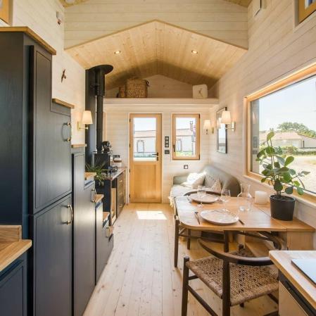 Esta atractiva minicasa presenta un exterior con un revestimiento de madera de dos tonos y un techo de aluminio de color negro.