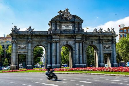 Un motorista circulando por Madrid, en la Puerta de Alcalá 