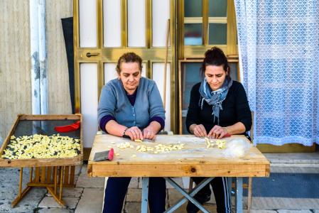 Dos mujeres preparan artesanalmente en la calle, frente a su casa de Bari, las tradicionales 'orecchiette'