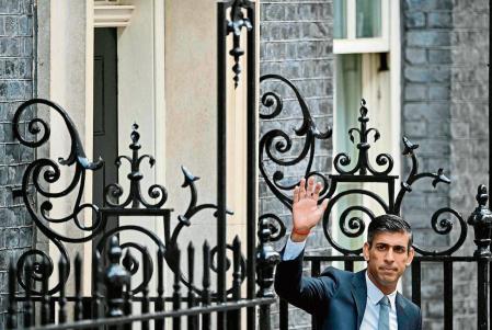 Britain's newly appointed Prime Minister Rishi Sunak waves as he poses outside the door to 10 Downing Street in central London, on October 25, 2022, after delivering his first speech as prime minister. - Rishi Sunak was on Tuesday appointed as Britain's third prime minister this year, after outgoing leader Liz Truss submitted her resignation to King Charles III. (Photo by JUSTIN TALLIS / AFP)