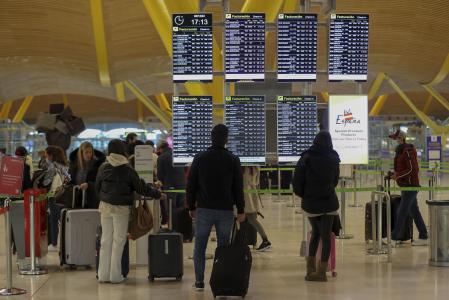 Viajeros consultan vuelos en el aeropuerto de Madrid, este puente