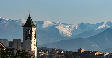 El campanario restaurado de la Gleva con el Pirineo nevado de fondo.