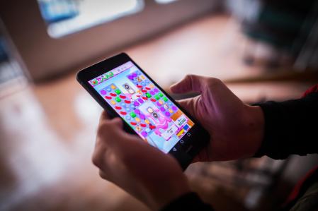 Bucharest, Romania - January 25, 2017: Close up illustrative editorial shot of a person's hands, holding a smartphone and playing Candy Crush Saga game.