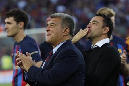 Barcelona club President Joan Laporta, centre and head coach Xavi Hernandez applaud and blow kisses to the fans at the end of a Spanish La Liga soccer match between Barcelona and Mallorca at the Camp Nou stadium in Barcelona, Spain, Sunday, May 28, 2023. (AP Photo/Joan Monfort)