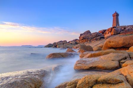 Ploumanach lighthouse or Phare de Men Ruz at the pink granite coast in Brittany, France during a beautiful summer sunset.