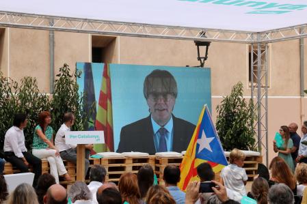 Puigdemont en un mítin de Junts a través de una pantalla