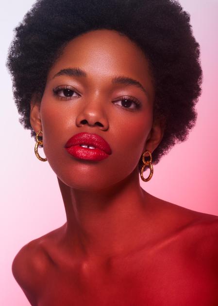 Protagonista: la barra de labios Fabulous Kiss Efecto Glitter en el tono Rojo 310 Glitz. El colorete líquido Good Girl Rosewood Peonia–Rojo 1012 y el iluminador Fabulous Skin Highlighter la acompañan. Pendientes Iris CH Carolina Herrera