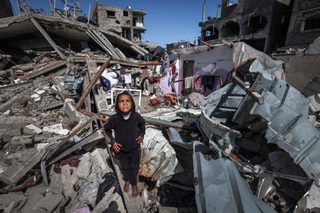 A Palestinian girl looks up to watch a military drone (not in the picture) as she stands on the rubble of destroyed houses in the Rafah refugee camp in the southern Gaza Strip, on March 21, 2024, amid ongoing battles between Israel and the militant group Hamas. (Photo by MOHAMMED ABED / AFP)
