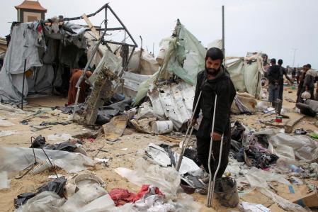 A man looks on as Palestinians inspect a tent camp damaged in an Israeli strike during an Israeli military operation, in Rafah, in the southern Gaza Strip, May 28, 2024. REUTERS/Hatem Khaled TPX IMAGES OF THE DAY