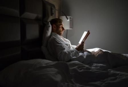 Un hombre leyendo un libro por la noche con luz.