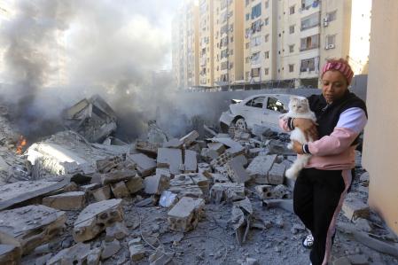 TOPSHOT - A woman carries a cat past a destroyed building at the site of an overnight Israeli airstrike in Beirut's southern suburb of Shayyah on October 2, 2024. At least five Israeli strikes hit Beirut's southern suburbs early October 2, a Lebanese security source said, as the Israeli military said it was targeting Hezbollah sites and issued several evacuation orders. (Photo by AFP)